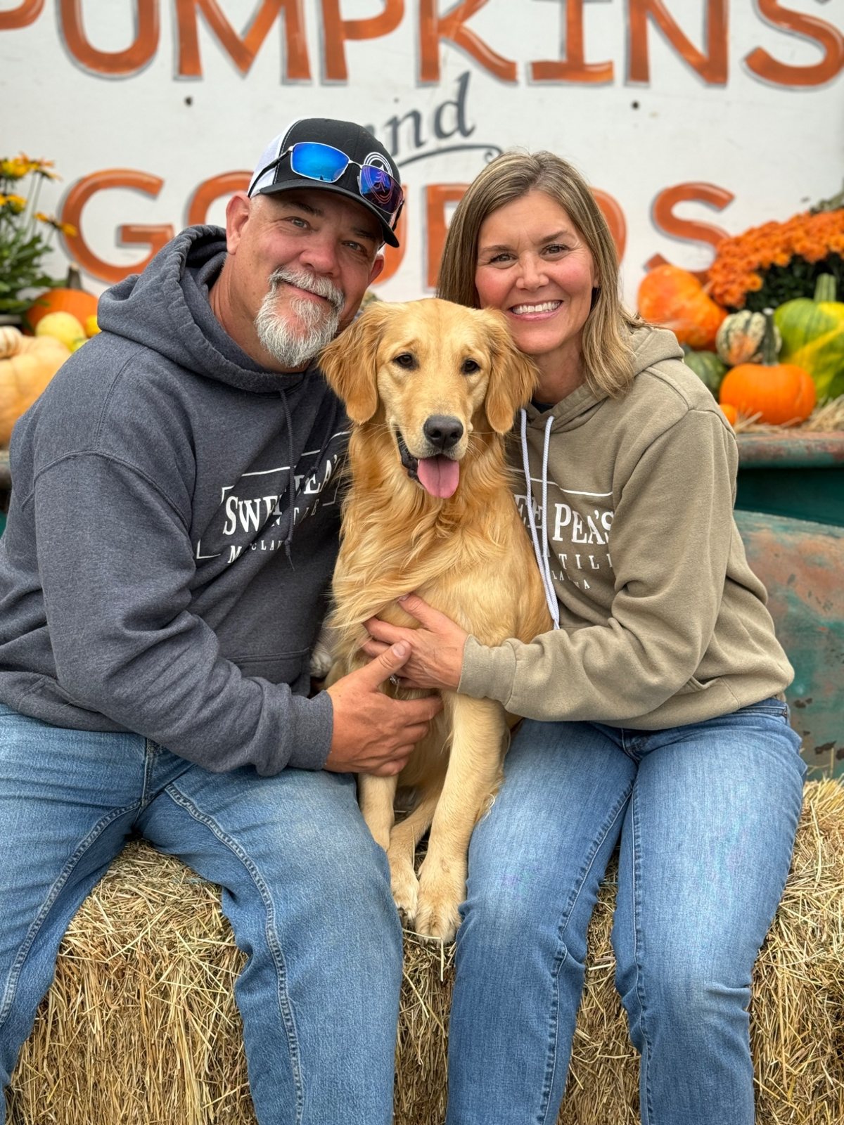 Carrie and Jeff, Mimi and Pops, sitting with Peanut among the pumpkins at Sweet Pea’s